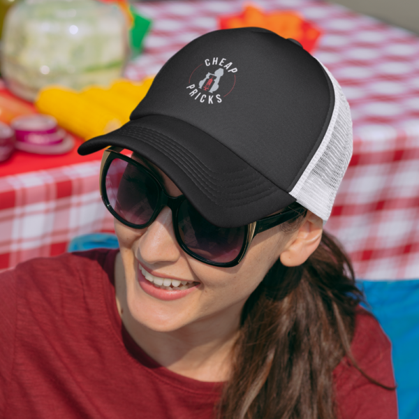 Female model wearing black trucker hat with white mesh and embroidered logo